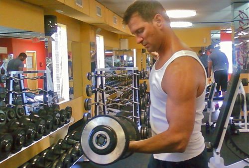 man curling dumbell in gym