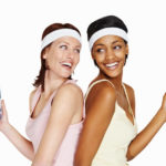 Two friendly women drinking water together after a workout.