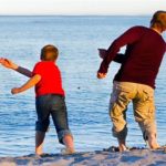 Father and son skip stones on water