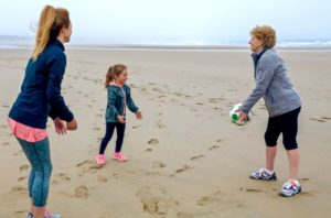 Three generations of females playing on the beach.